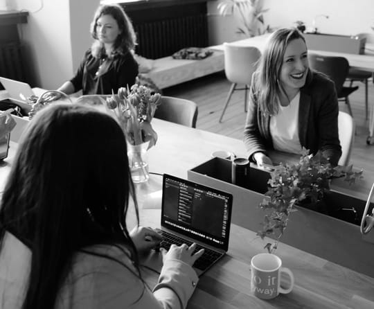 photo of a couple of people working on the computers and laughing